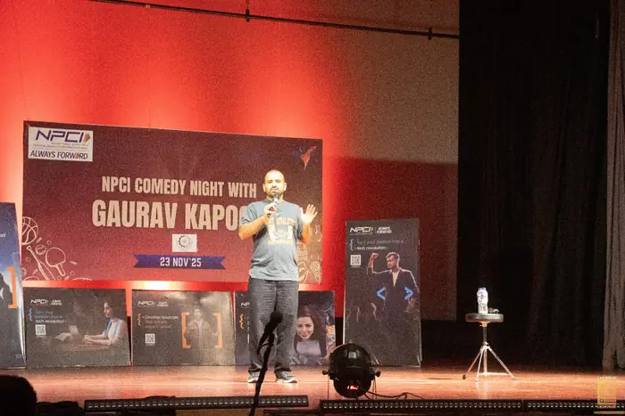 Gaurav Kapoor on stage at the 2025 comedy night, in front of the event banner