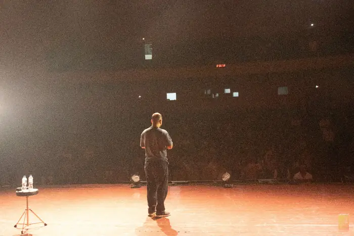 Gaurav Kapoor seen from behind, facing the packed auditorium
