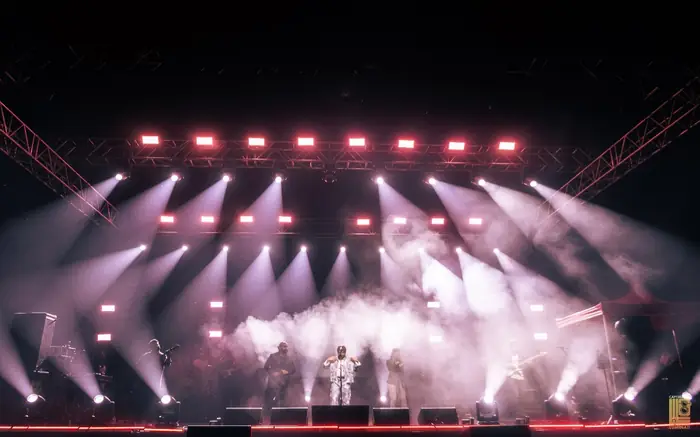 Ankit Tiwari performing under a rig of white spotlights and haze