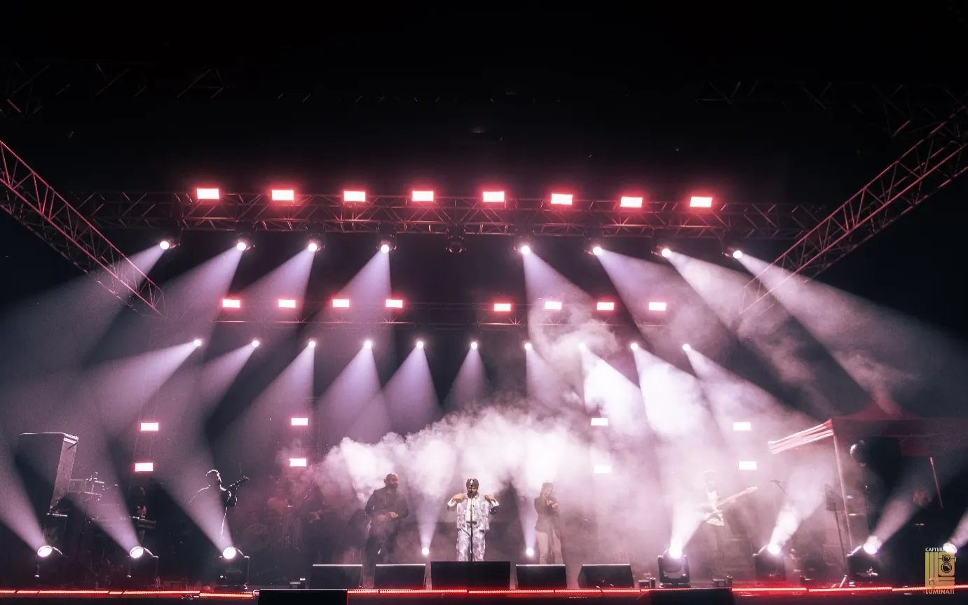 Ankit Tiwari performing under a rig of white spotlights and haze