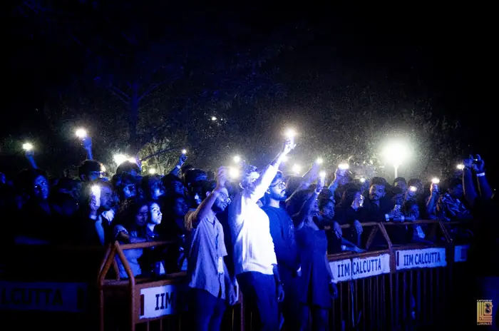 Crowd at the barricade holding up phone lights at the concert