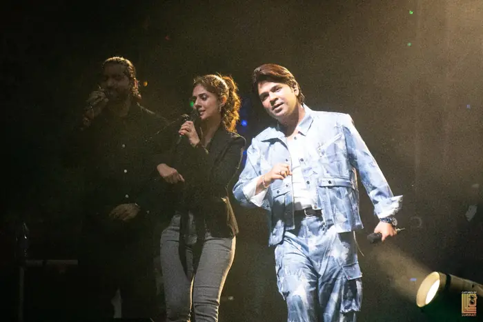Ankit Tiwari singing alongside two vocalists at the concert