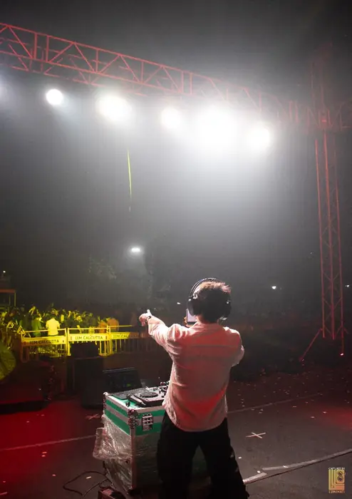 DJ at the decks facing the crowd, seen from the stage